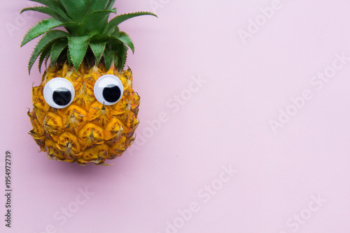 Pineapple with eyes on pink background