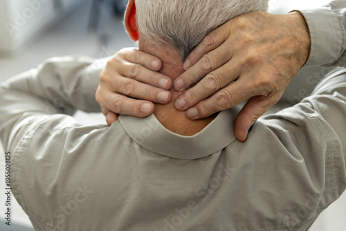 Foto Elderly man experiencing pain touching his sore neck
