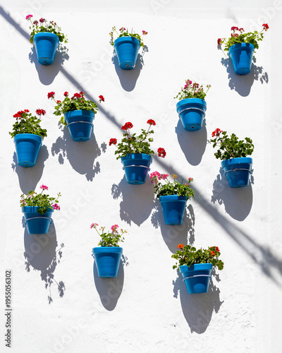 Colorful blue flower pots on white wall with shadows, Mediterranean style