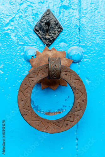 Rusty vintage door handle on blue wooden door, textured close up