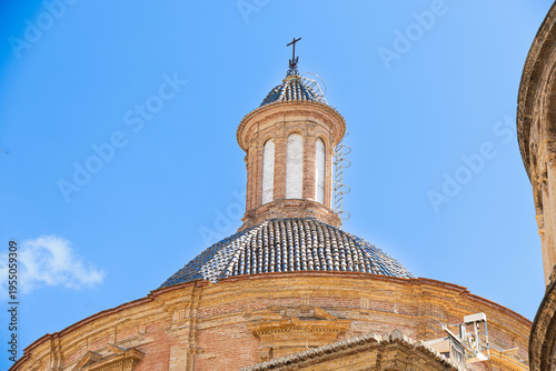 Historic church dome with cross against blue sky in Valencia Spain