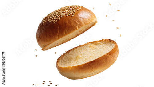 Isolated freshly baked sesame burger bun sliced in half, top piece floating above bottom.