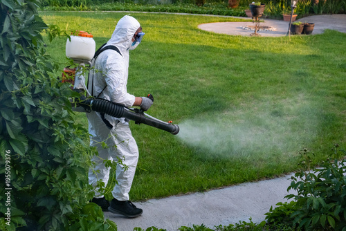 Spring garden pest control: man in protective suit spraying plants