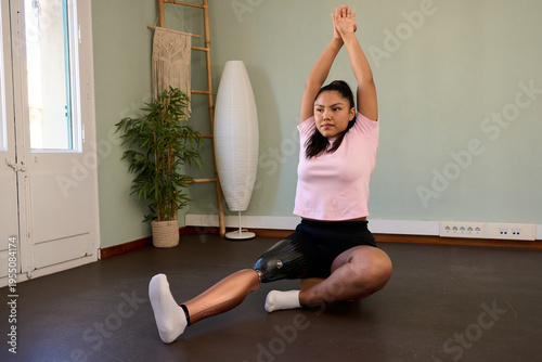 Woman with prosthetic leg practicing yoga stretching at home