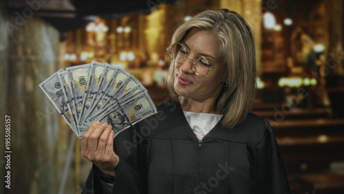 Fotografie Blonde judge woman wearing robe holds money fan inside church building altar area; greed