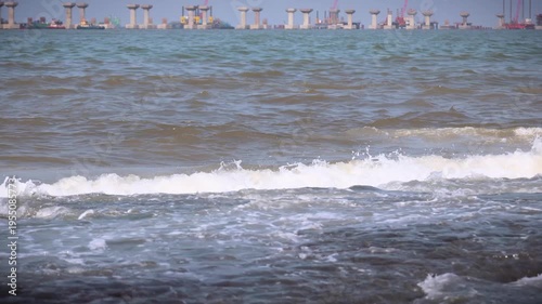 Mumbai Maharashtra India Jan 18 2026 Large waves crash against the rocky shoreline at Bandra with foamy surf and open Arabian Sea view in daylight.