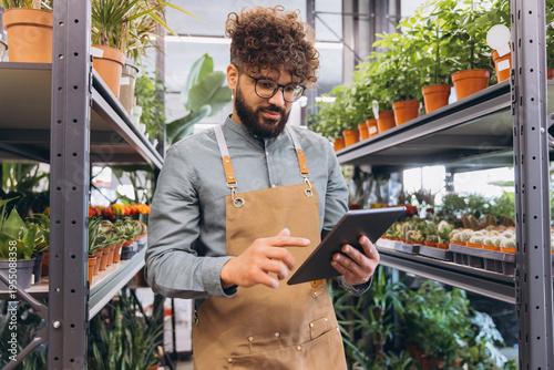 Florist small business owner using digital tablet checking plant inventory in a modern flower shop