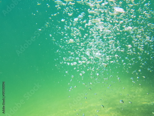 Air bubbles underwater in clear turquoise water abstract aquatic background
