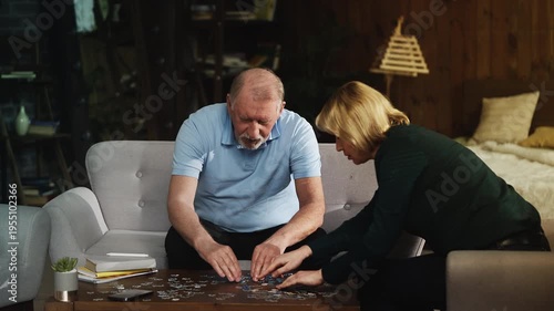 Senior man and adult daughter connecting jigsaw puzzle pieces, family pastime