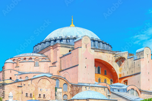 View of the historic Hagia Sophia Grand Mosque with its iconic pink facade under a clear blue sky in Istanbul, Turkey.