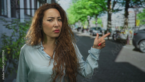 Wallpaper Mural Woman points finger to the right on street wearing light blue shirt with skeptical expression; frustration. Torontodigital.ca