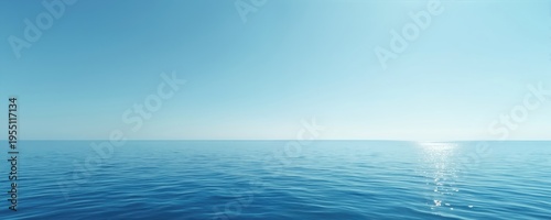 Vast blue ocean meets clear sky at horizon line. Calm water reflects bright sunlight creating sparkling path. Minimalist seascape offers ample copy space for text.