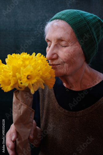 Elderly woman holds and smells yellow flowers
