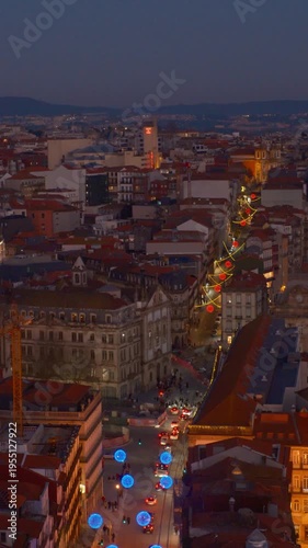 People tourists walking on street next to european style buildings, lit up by building lights at night and colorful street light decorations over cars driving no road vertical