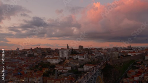Beautiful pink sunset golden hour hitting the red roof tops of Porto buildings and the peaceful river, as tourists people walk about