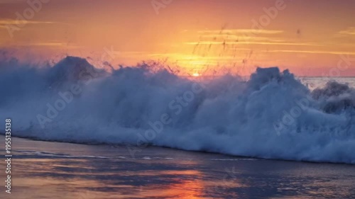 Epic ocean wave crashing on the sandy beach during a beautiful sunset with vibrant orange and purple colors