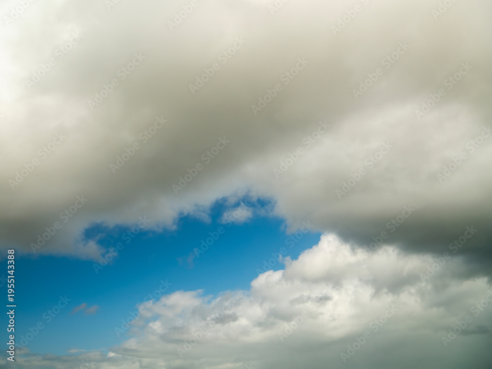 Obraz premium Blue cloudy sky. Nature background for design. Random shape. Calm cloudscape.
