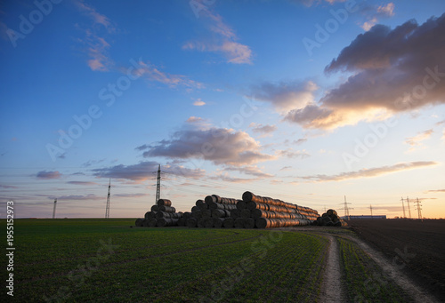 Countryside Landscape with Hay Bales and Power Infrastructure at Golden Hour