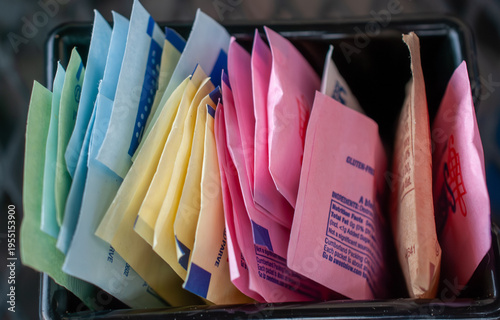 Cuadro en lienzo Assortment of vibrant artificial sweetener packets in a caddy, offering various sugar substitutes like Splenda, Sweet'n Low, and Stevia for coffee and tea, promoting a healthy, low-sugar lifestyle