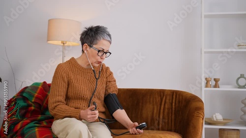 Mature woman measuring blood pressure at home