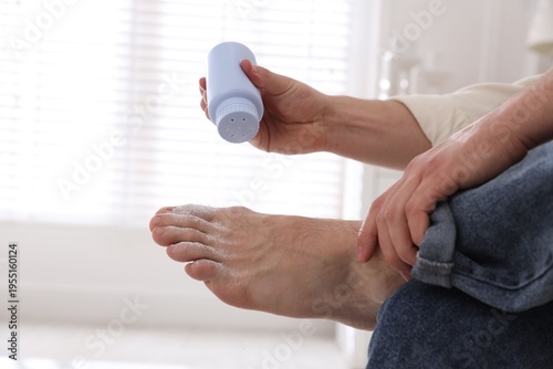 Konstfotografi Man applying talcum powder onto his foot at home, closeup