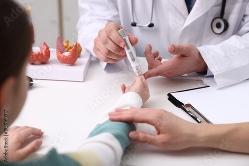Foto Endocrinologist checking little girl's blood sugar level with lancet pen while h
