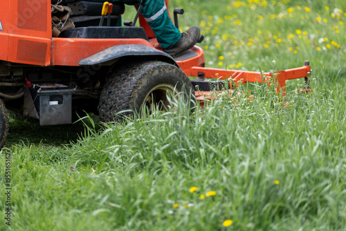 Foto Commercial mower approaching overgrown lawn with wild grass