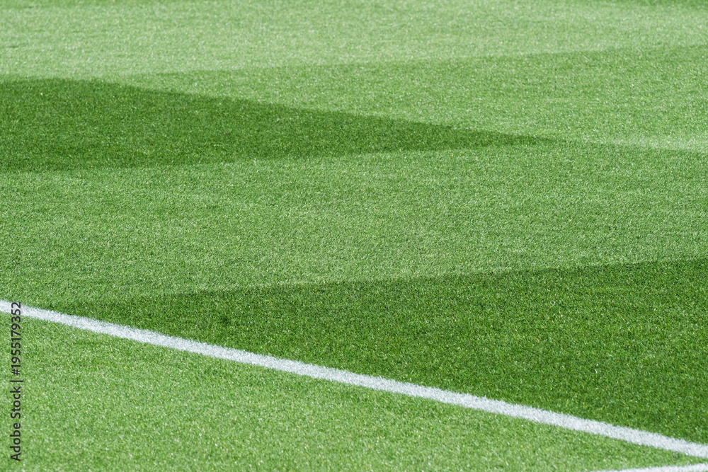 Obraz premium Well-Maintained Football Stadium Pitch with Striped Grass Under Clear Blue Sky