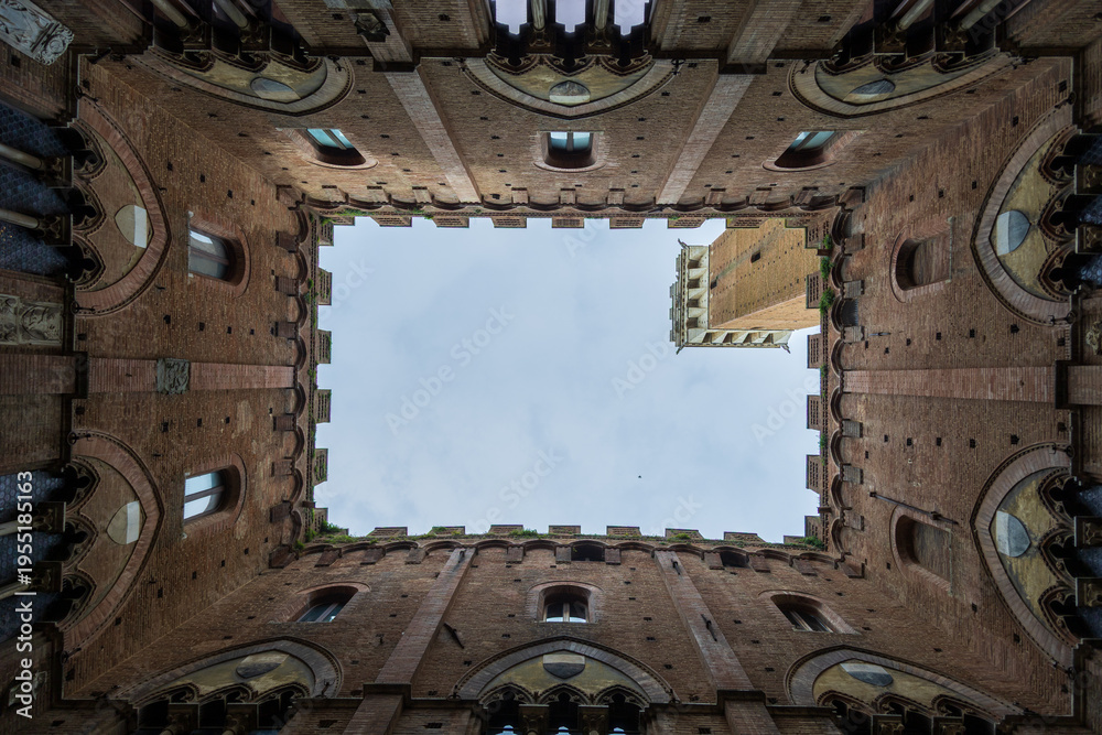 Fototapeta premium Medieval Courtyard Scene. Ancient Siena Tower Framed Beautifully. Charming Medieval Setting Showcasing Terracotta Tones And Architectural Details
