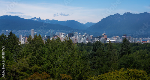 Elevated view of Vancouver skyline with North Shore Mountains and Queen Elizabeth Park trees - Vancouver, British Columbia, Canada
