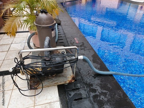 Operational swimming pool pump and filtration system diligently maintaining clean and clear water, positioned alongside a sparkling blue backyard pool for optimal aquatic enjoyment