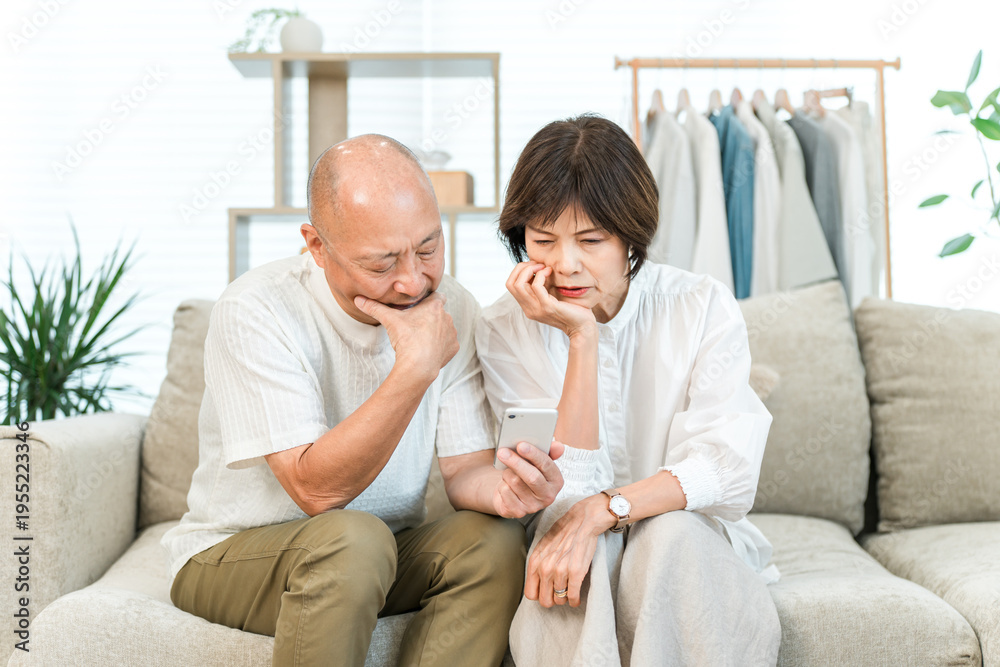 Fototapeta premium An elderly Asian couple using smartphone apps (confusing, confused, finding it difficult, feeling anxious)