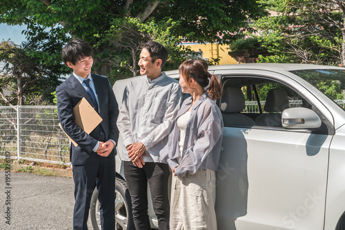 Konstfotografi A young Asian male salesman serving customers who have come to buy, appraise, or sell their cars