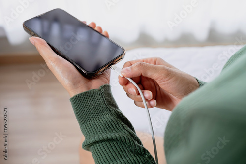 Canvastavla Close-up of woman hands plugging USB cable into smartphone