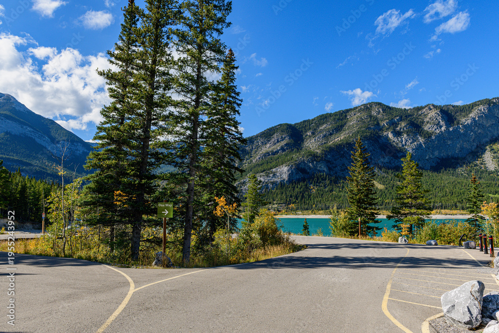 Naklejka premium One-way sign near parking area overlooks Barrier Lake, with pine trees framing mountain vista 