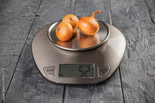 Fresh Onions on Digital Kitchen Scale Displaying Weight on Rustic Wooden Surface