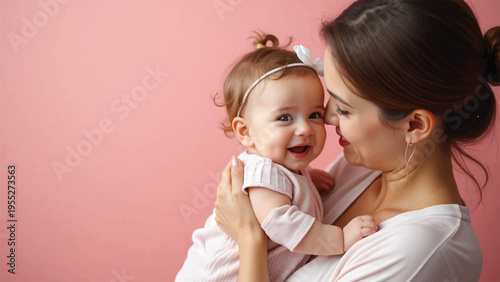 Mother holding baby girl in pink background