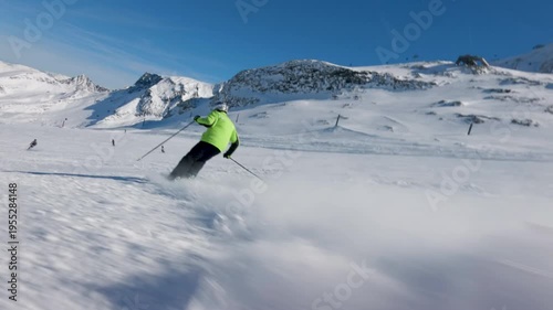 Mountain skier carve turns on a pristine snowy piste during a clear winter day. Low angle slow motion view	