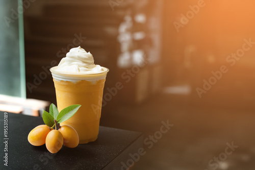 Refreshing Marian plum smoothie topped with creamy cheese foam, served in a clear cup with fresh Marian plums, warm light ambiance