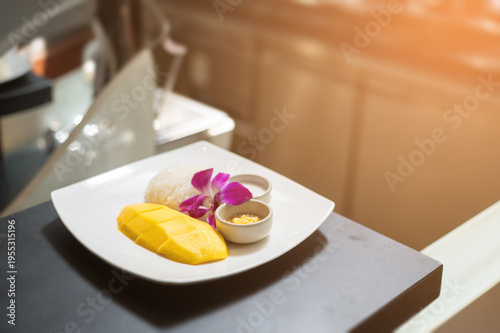 Traditional mango sticky rice served with ripe mango slices, sweet coconut sticky rice, and creamy coconut sauce, elegantly plated with orchid garnish