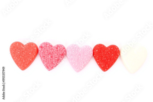 Five heart shaped candies in a row with red pink and white colors on a plain white background