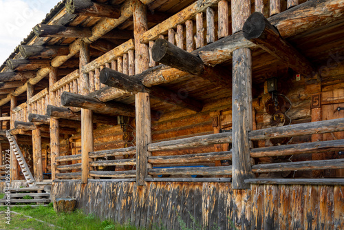 The impressive wooden walls of a reconstructed Old Slavic fortress, made of round, hewn logs. Old barracks and boyar chambers. A bright, sunny day.
