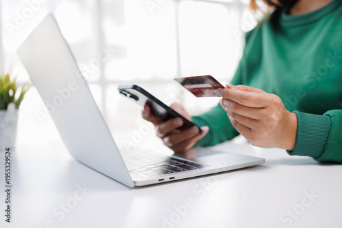 A focused individual is depicted while shopping online, holding a credit card and mobile phone in a casual setting, reflecting the evolving nature of consumer behavior in the digital age.