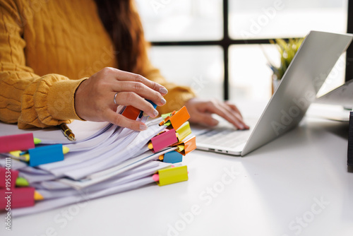 Foto This engaging image features a person managing papers with colorful sticky notes around a laptop, reflecting a detailed planning process and systematic approach