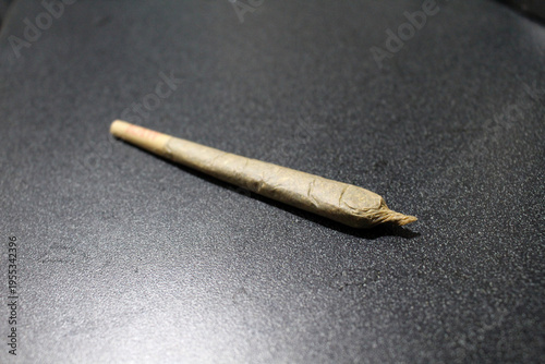 Joint of weed on dark surface September 2024 rolled cannabis cigarette on textured black background