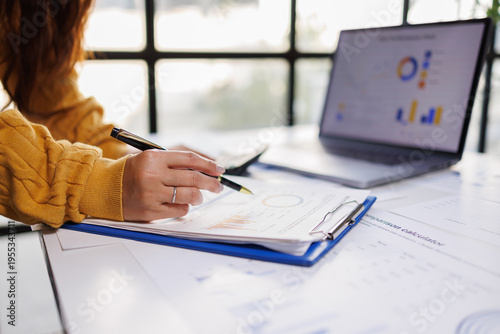 Obraz na plátne An individual meticulously reviewing business documents in a modern office setting, highlighting the importance of attention to detail and productivity in professional environments