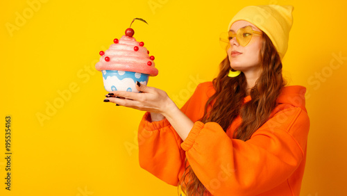 Woman with yellow beanie and glasses presents oversized dessert