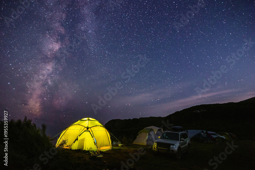 Tourist camping near the sea under the night sky with milky way.