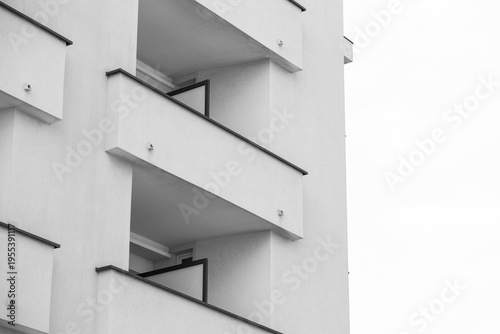 View from below of the facade of a building, close up on the geometrical features of the balconies. Modern residential concrete design.