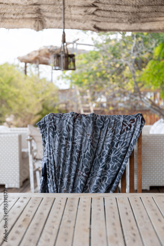 Colorful pareo or sarong left on the back of a chair on the porch of a tropical beach house. Summer vacation mood, carefree, relaxation mood.